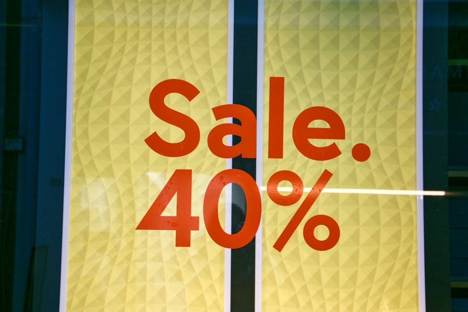A close-up view of a promotional window display featuring a large, bold red sign announcing a 40% sale. The background consists of a yellow geometric pattern with subtle diamond shapes, framed by a da